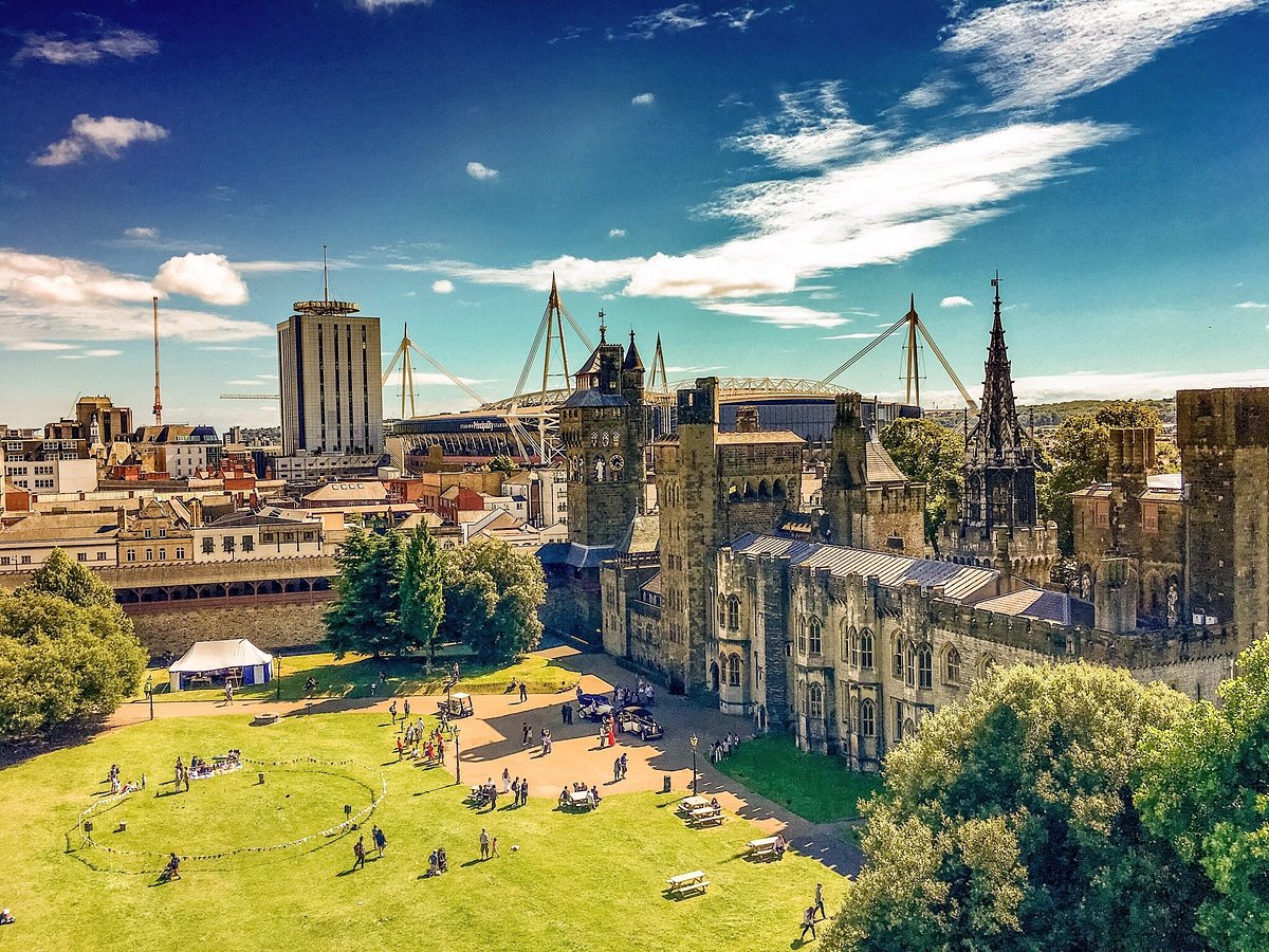 Aerial view of Cardiff Castle grounds with the Principality Stadium and city skyline under a blue summer sky